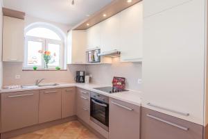 uma cozinha com armários brancos, um lavatório e uma janela em Villa Symphonie em Porec