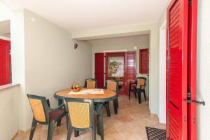 uma sala de jantar com uma porta vermelha e uma mesa e cadeiras em Villa Symphonie em Porec