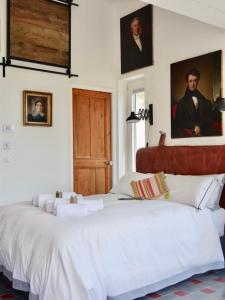 ヴァンスにあるL'Atelierの白い大型ベッドと壁に描かれた肖像画が備わるベッドルーム1室が備わります。