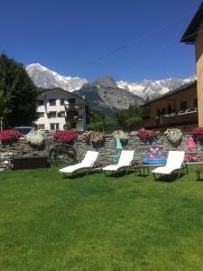 a group of lounge chairs on a lawn with mountains in the background at La Boule de Neige in Pré-Saint-Didier
