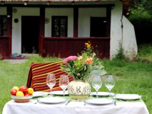 a table with wine glasses and a vase of flowers at Casa Memoriala George Stephanescu in Căpăţîneni-Ungureni