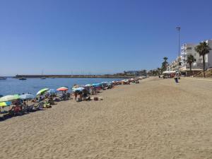 ロケタス・デ・マルにあるLa Perla Azul Playa - Terraza al Solの傘をさして浜辺に座る人々