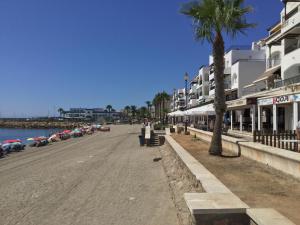 a beach with a palm tree and some buildings at La Perla Azul Playa - Terraza al Sol in Roquetas de Mar