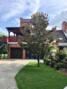 ein Haus mit einem Baum im Vorgarten in der Unterkunft Laza Vendégház in Zamárdi