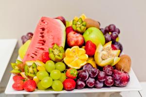 a plate of fruits and vegetables on a table at JB Palace Hotel in Divinópolis +52 photos