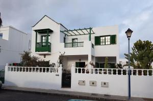 ein weißes Haus mit grünen Fenstern und einem weißen Zaun in der Unterkunft Chelada 2 in Arrieta