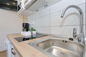 a kitchen with a stainless steel sink and white tiles at Two new apartments by the town center in Zadar +44 photos