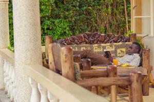 un homme assis à une table sur un canapé dans l'établissement Entebbe Vine Inn, à Entebbe