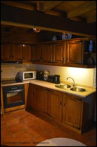 a kitchen with wooden cabinets and a sink and a microwave at Castelo Cottages II in Monsanto