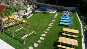 un parque infantil con sillas azules y bancos en el césped en Residence Vellauerhof en Lagundo