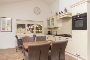 cocina con mesa, sillas y microondas en Lenthe Farm Lodge, en Dalfsen