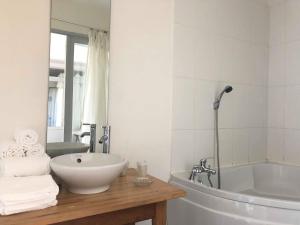a bathroom with a sink and a tub and a mirror at Le Pavillon Bleu in Cap-Ferret