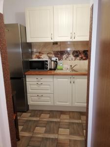 eine Küche mit weißen Schränken und einem Kühlschrank aus Edelstahl in der Unterkunft Apartament Wiktoryn in Lublin