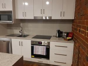 a kitchen with white cabinets and a stove top oven at Sublime Spa Apartments in Wangaratta