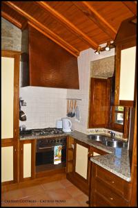 a kitchen with wooden cabinets and a stove top oven at Castelo Cottages in Castelo Novo