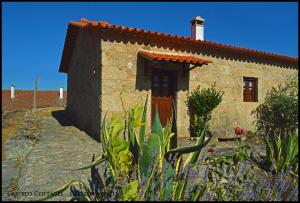 a stone house with a red door and some flowers at Castelo Cottages in Castelo Novo