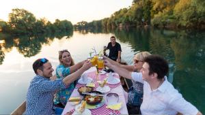 a group of people sitting at a table on a boat in the water at Apartman AS in Bihać
