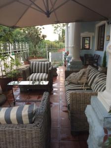 an outdoor patio with wicker couches and an umbrella at Melville Turret Guesthouse in Johannesburg