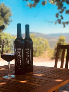 two bottles of wine sitting on a wooden table with a glass at Quinta Pecêga - AL in Peso da Régua