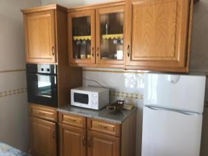 una cucina con armadi in legno e forno a microonde bianco di Hospedaria A Primorosa a Nazaré