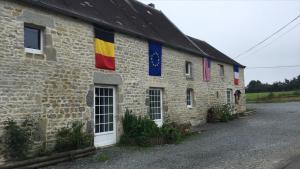 a stone building with flags on the side of it at chevrerie de la huberdiere in Liesville-sur-Douve