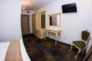 a bedroom with a bed and a desk and a television at Vila Seva in Vatra Dornei