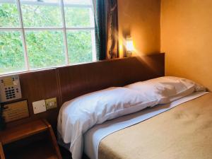 uma cama num quarto com uma grande janela em The Beverley House Hotel em Londres