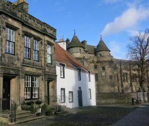 un vecchio edificio con un castello sullo sfondo di The Studio at Maspie House a Falkland