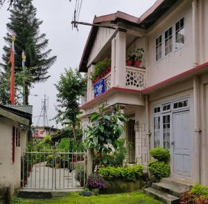 dom z białymi drzwiami i balkonem w obiekcie Deki Lodge w mieście Kalimpong