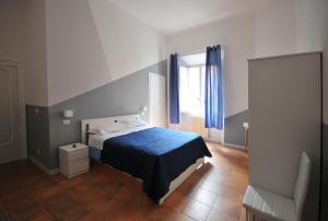Un dormitorio con una cama con una manta azul y una ventana. en Le Pignattelle B&B, en Siena