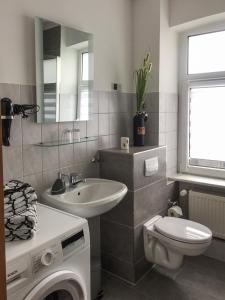 a bathroom with a sink toilet and a washing machine at Ferienwohnung am Schlossparkcenter in Schwerin