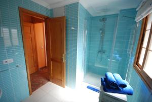 baño azul con ducha de azulejos azules en Beach Holiday Home Fue, en Gran Tarajal