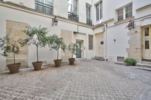 an empty courtyard with potted trees in a building at 69 - Authentic Parisian Home in Paris