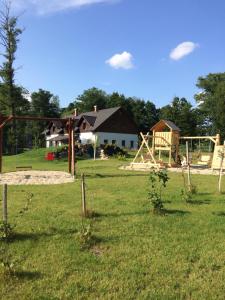 un parco giochi in un campo con una casa sullo sfondo di Penzion Terezka a Králíky