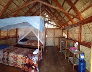 a bedroom with a canopy bed and a table at Beach Hut by S.A.R. in Waingapu