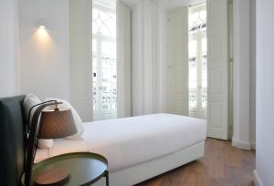 a white bedroom with a bed and a lamp at Spot Apartments Casa Januario in Porto