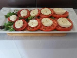 a plate of tomatoes with cheese and greens on it at B&B Villa Oasa 1 in Rovinj