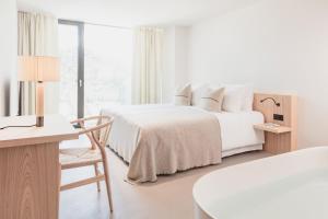 a white bedroom with two beds and a table and chair at Schgaguler Hotel in Castelrotto