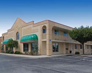 a hotel building with a green awning and a parking lot at Baymont by Wyndham Sandusky in Sandusky