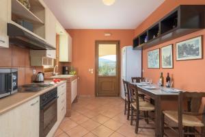 a kitchen with a table and chairs and a kitchen with orange walls at Villa Lahania in Lachania