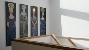 una fila di quattro dipinti di donne su un muro di Bed & Coffee Maricoweg a Den Burg