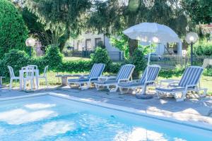 eine Gruppe Stühle und ein Sonnenschirm neben einem Pool in der Unterkunft Villa San Carlo in Cortemilia