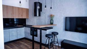 a kitchen with a bar with stools and a tv at Apartament Wrocławska 29 in Legnica
