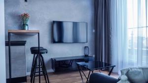 uma sala de estar com uma mesa e uma televisão na parede em Apartament Wrocławska 29 em Legnica