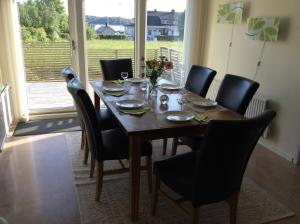 mesa de comedor con sillas negras, mesa de madera y ventana en Nösund Holiday Home en Nösund