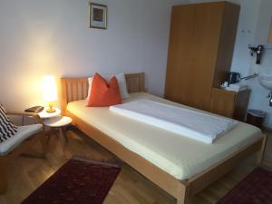 a bedroom with a bed with orange pillows and a lamp at B&B Elfi in Salzburg