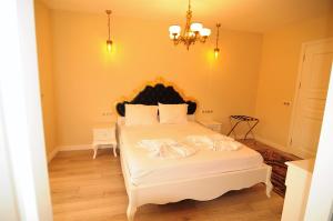 a bedroom with a large white bed with a chandelier at Grand Alaçatı Butik Hotel in Alaçatı