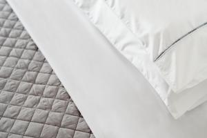 un letto chiuso con lenzuola bianche di Elia Residences Santorini a Karterados