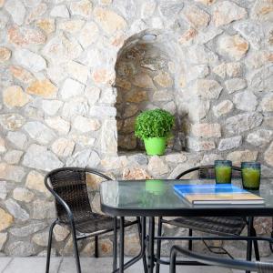 a table and chairs in front of a stone wall at Elia Residences Santorini in Karterados