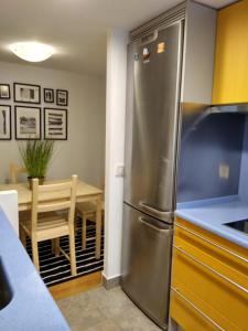 Il comprend une cuisine équipée d'un réfrigérateur en acier inoxydable et d'une table. dans l'établissement Apartamento Mercaderes, à Pampelune